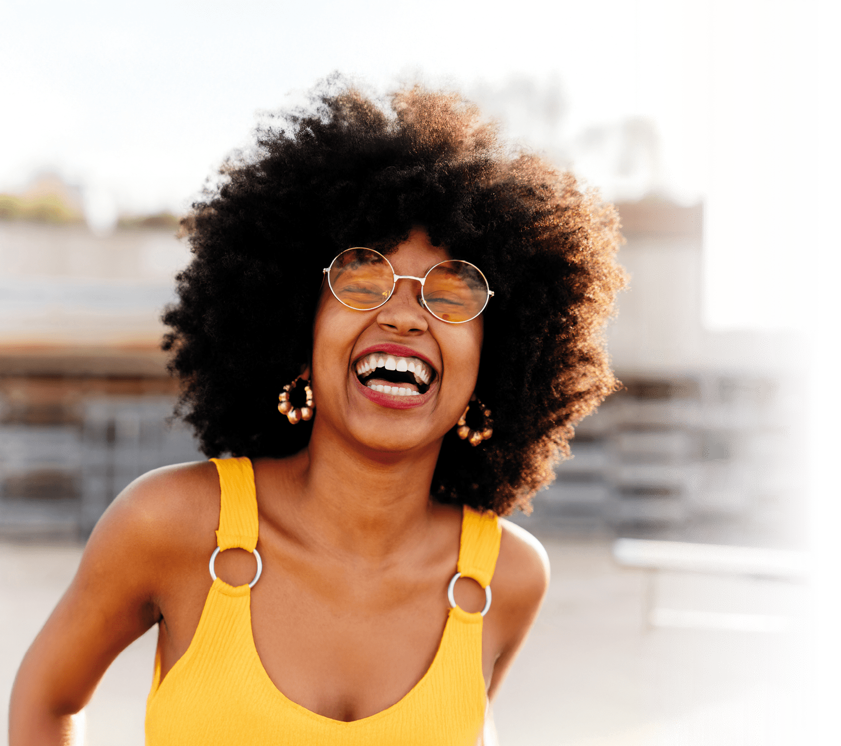 Beautiful young happy african woman with afro curly hairstyle strolling in the city - Cheerful black student portrait outdoors