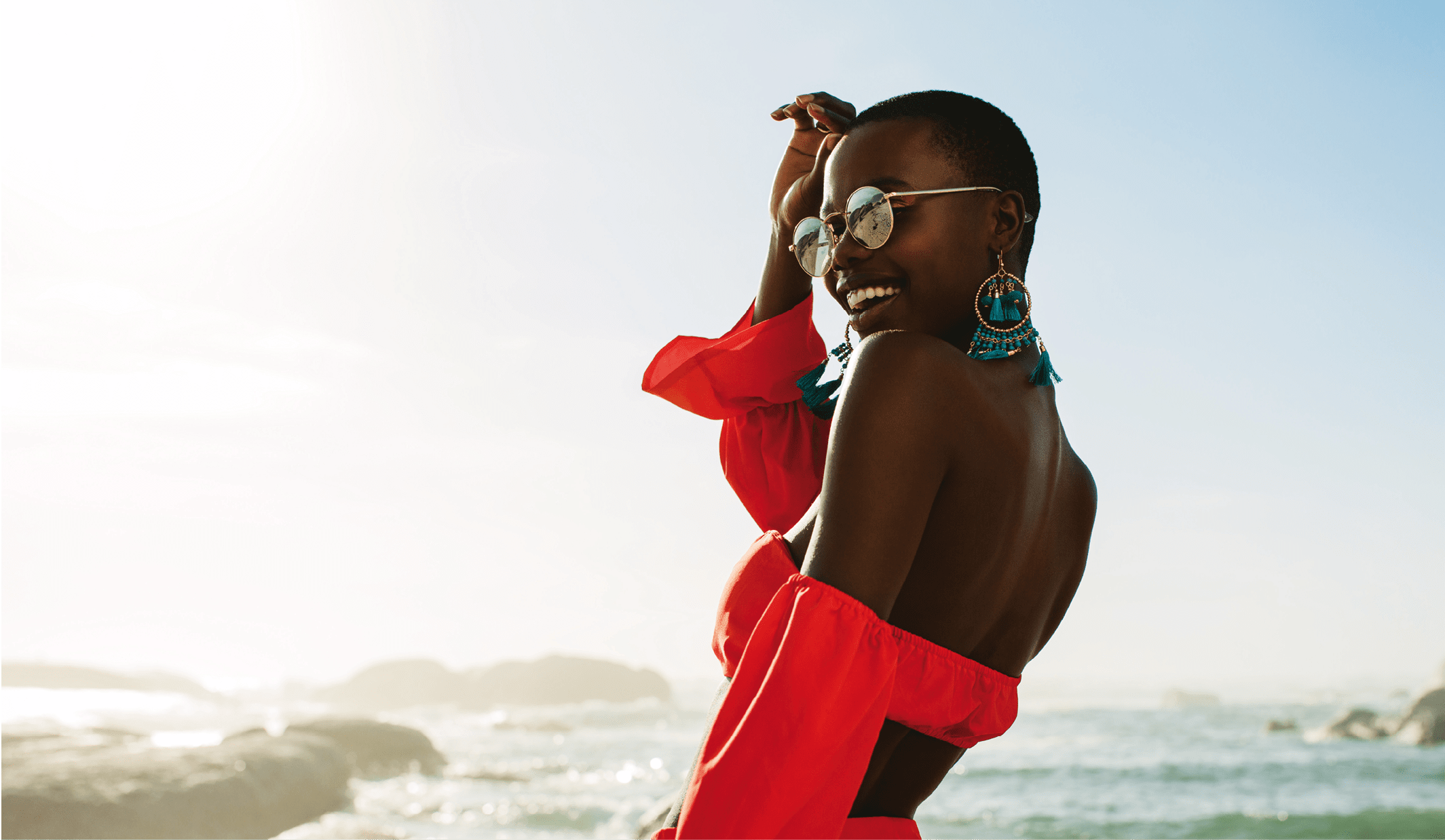 Beautiful african woman in red dress enjoying on the beach. Smiling female in beautiful dress walking along the shore.