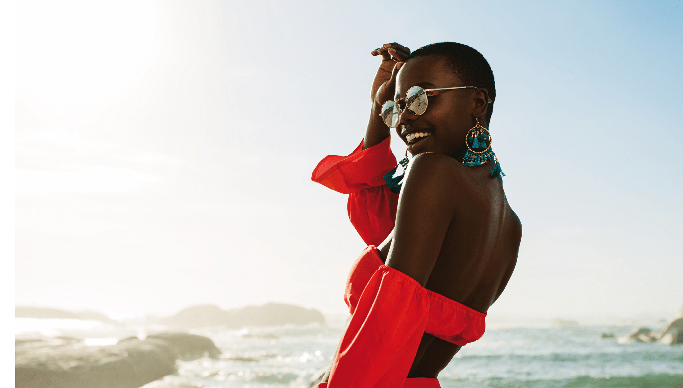 Beautiful african woman in red dress enjoying on the beach. Smiling female in beautiful dress walking along the shore.