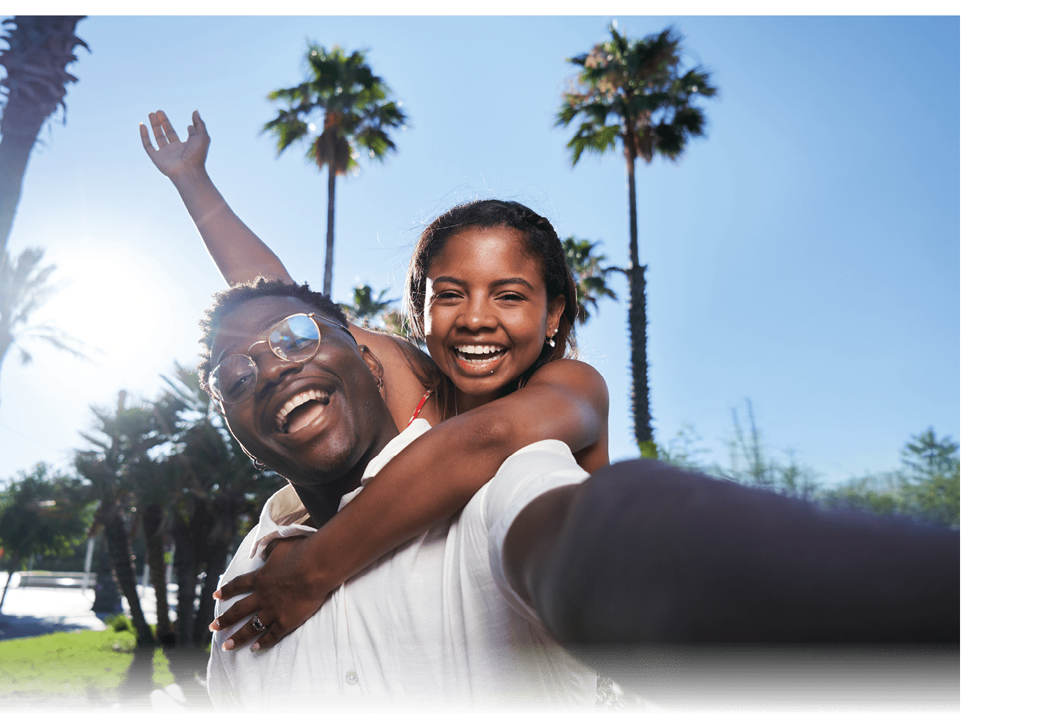 Cheerful selfie of a young African American couple on their summer vacation on an island. African man giving piggyback ride to his Latina girlfriend. Social media sharing.
