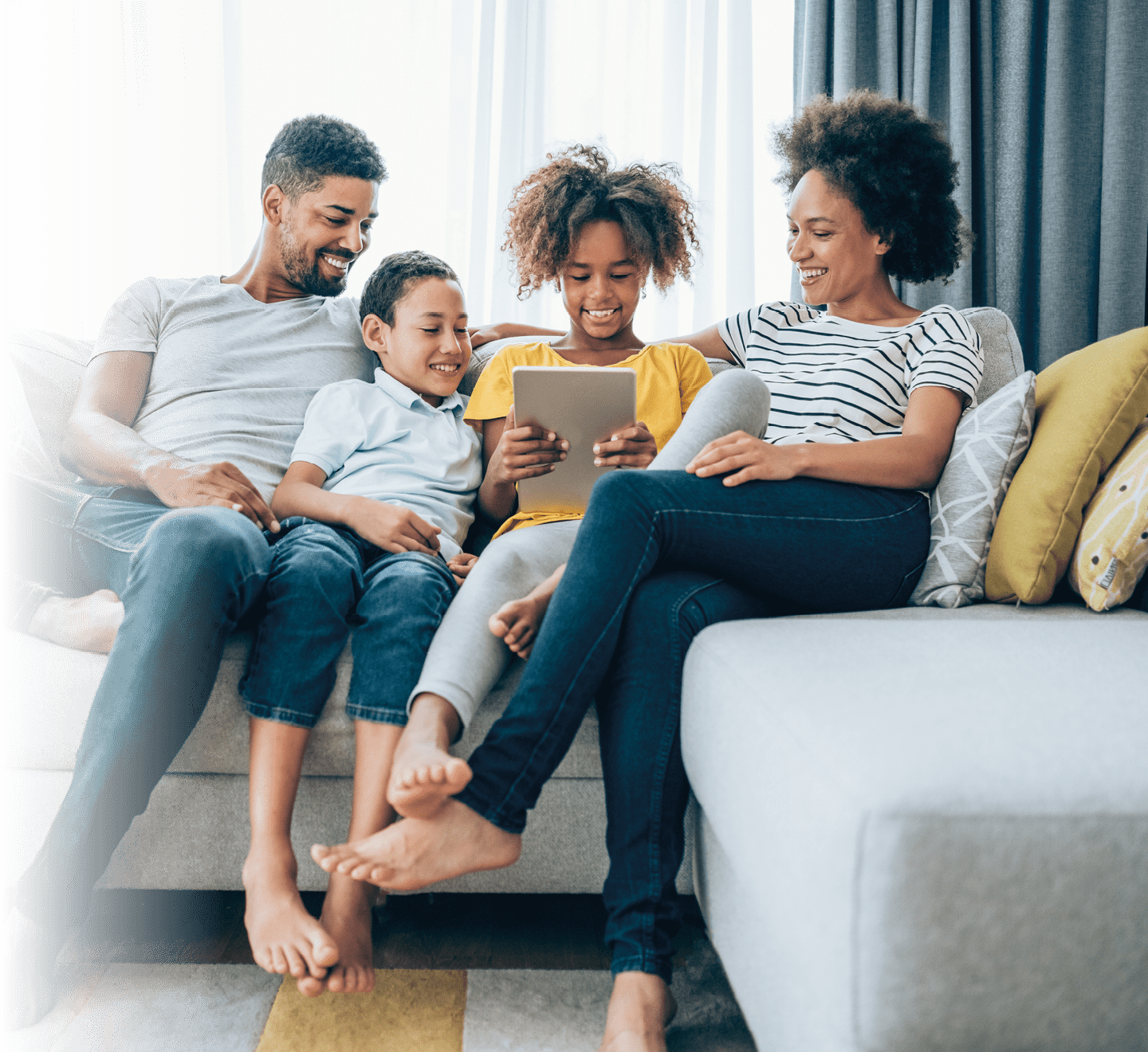 Shot of a smiling family with two kids using digital tablet on the sofa at home.