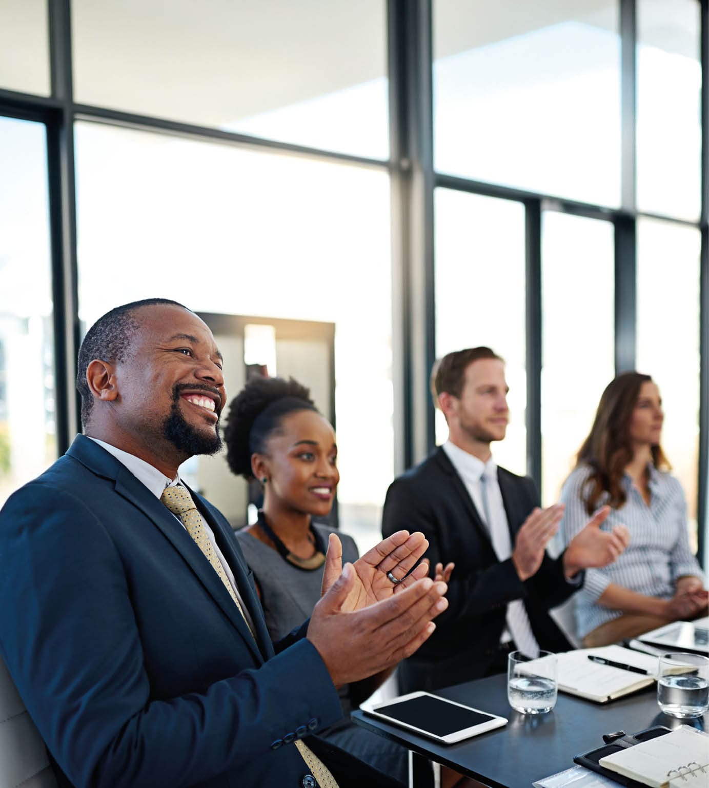 Shot of a group of corporate businesspeople applauding while sitting in the boardroom