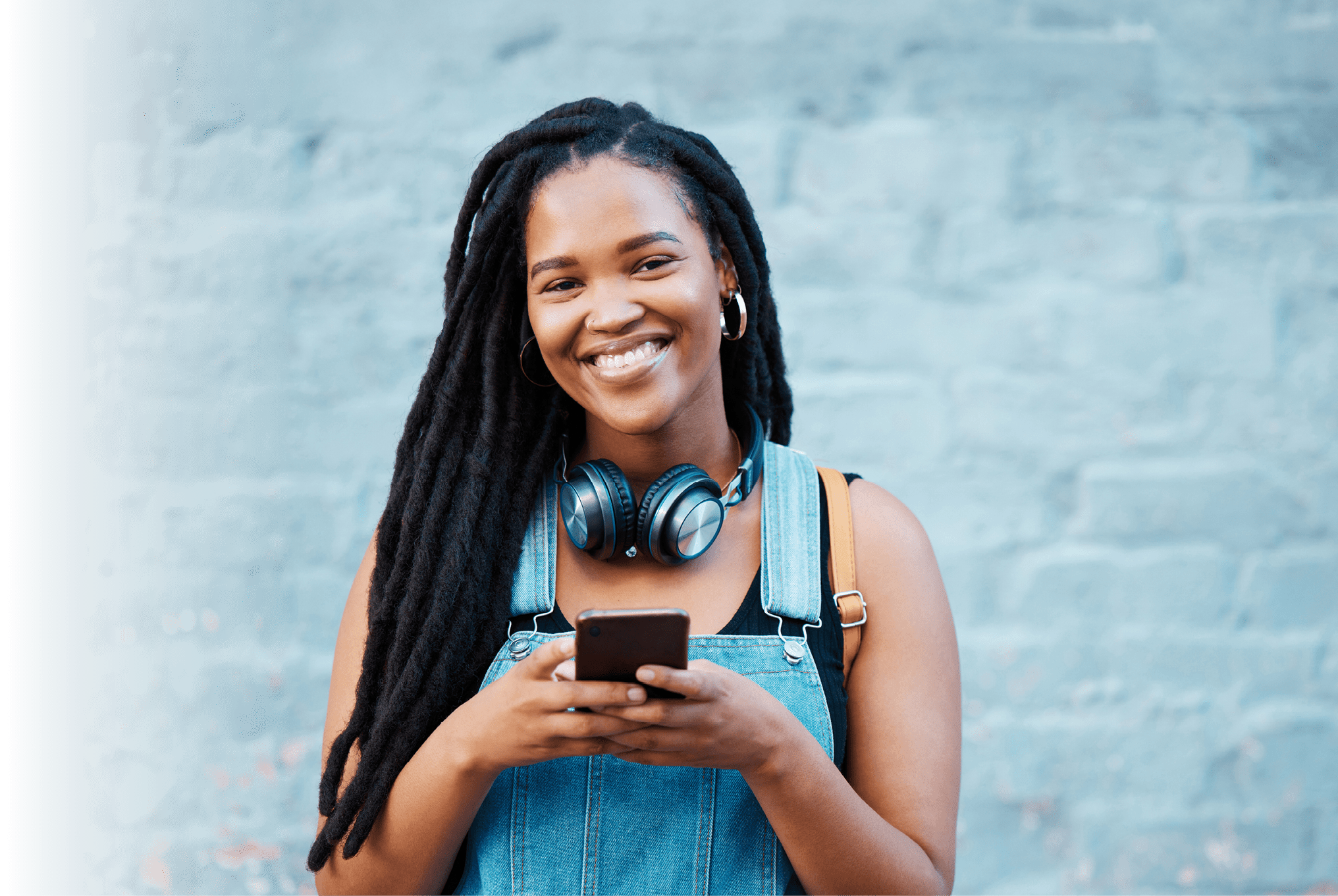 Black woman, happy and phone in city on travel, walk or adventure in urban street. Girl, smartphone and smile against wall in Atlanta on vacation, holiday or break while in communication online
