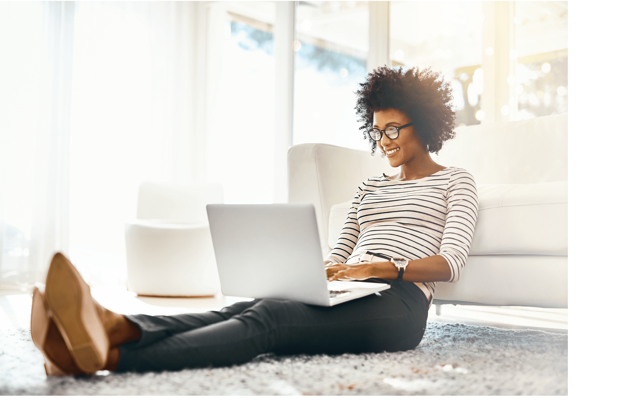 Shot of a cheerful young woman doing online shopping on her laptop while being seated on the floor at home