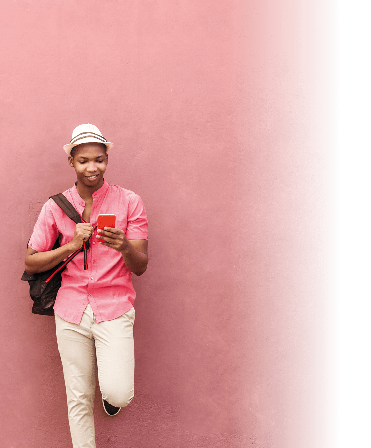Latin american man with backpack and hat stand over a colorful wall looking a smartphone mobile.