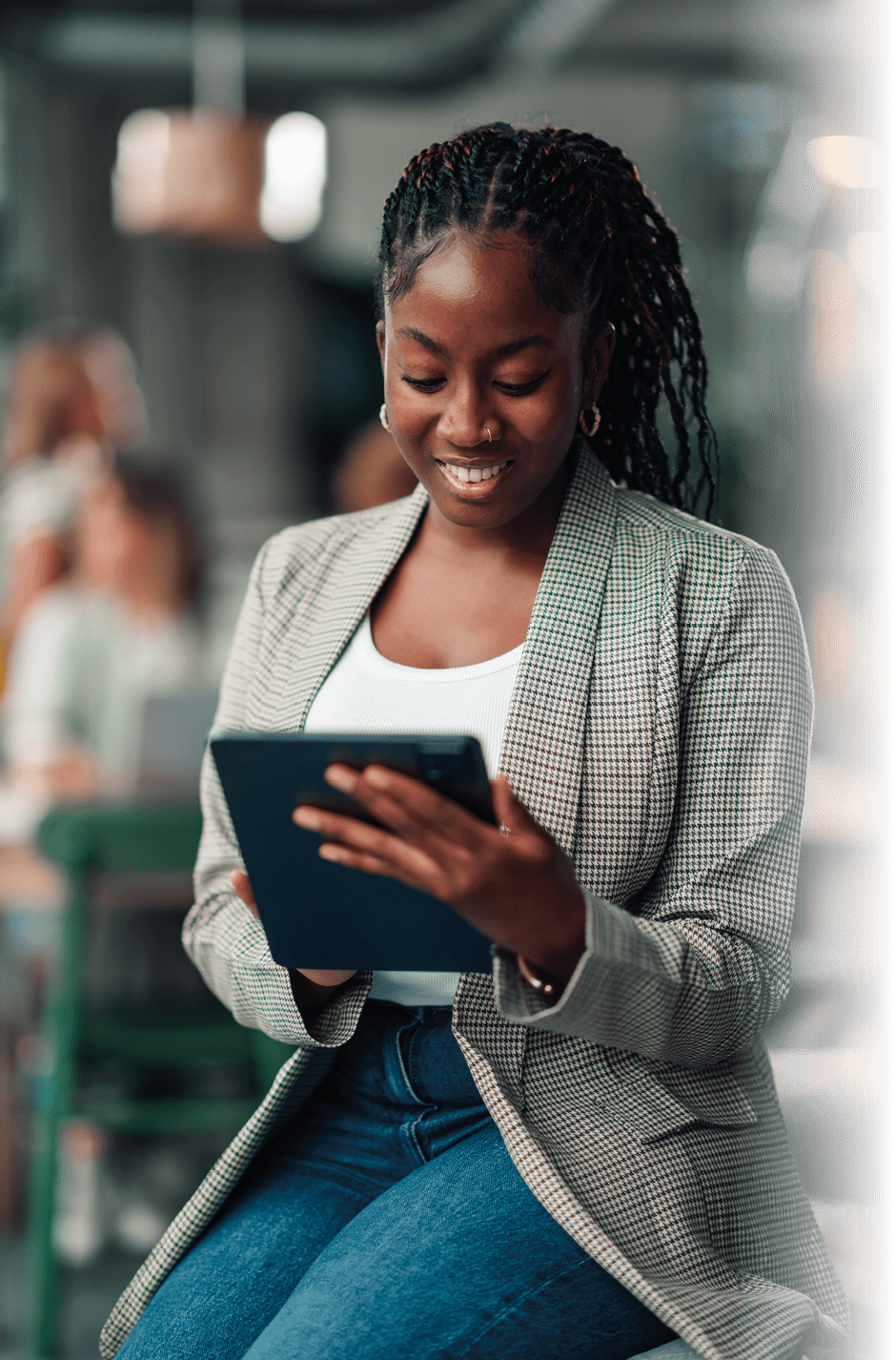 Young black woman smiling and working on a digital tablet, focused and engaged in a modern office environment