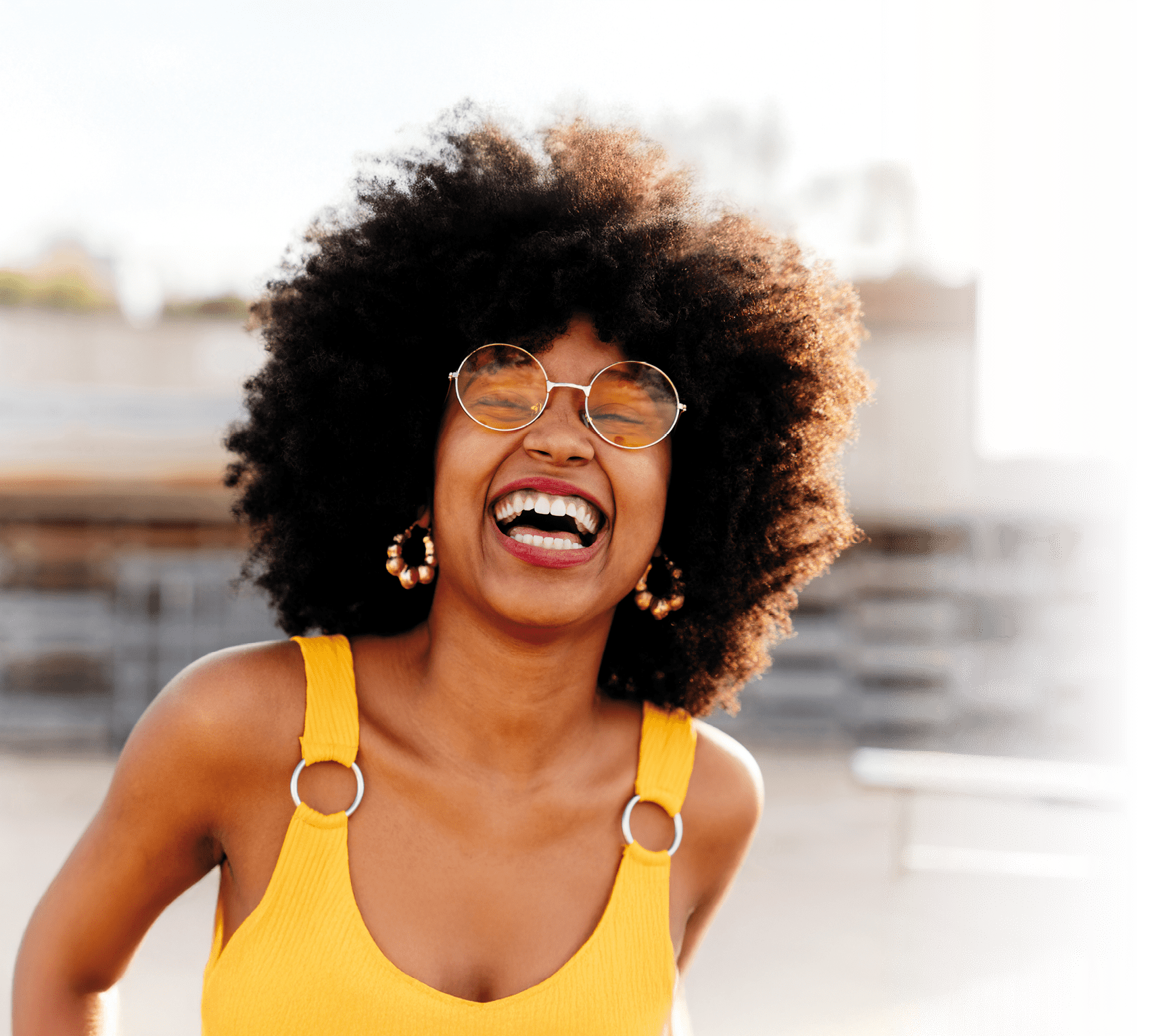 Beautiful young happy african woman with afro curly hairstyle strolling in the city - Cheerful black student portrait outdoors