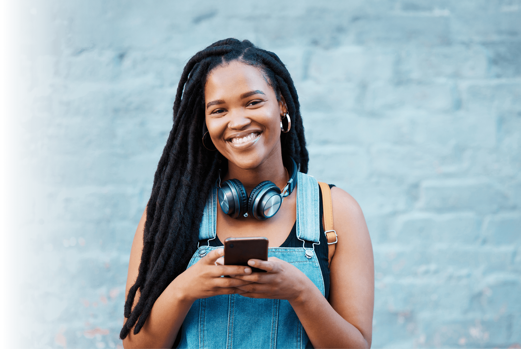 Black woman, happy and phone in city on travel, walk or adventure in urban street. Girl, smartphone and smile against wall in Atlanta on vacation, holiday or break while in communication online