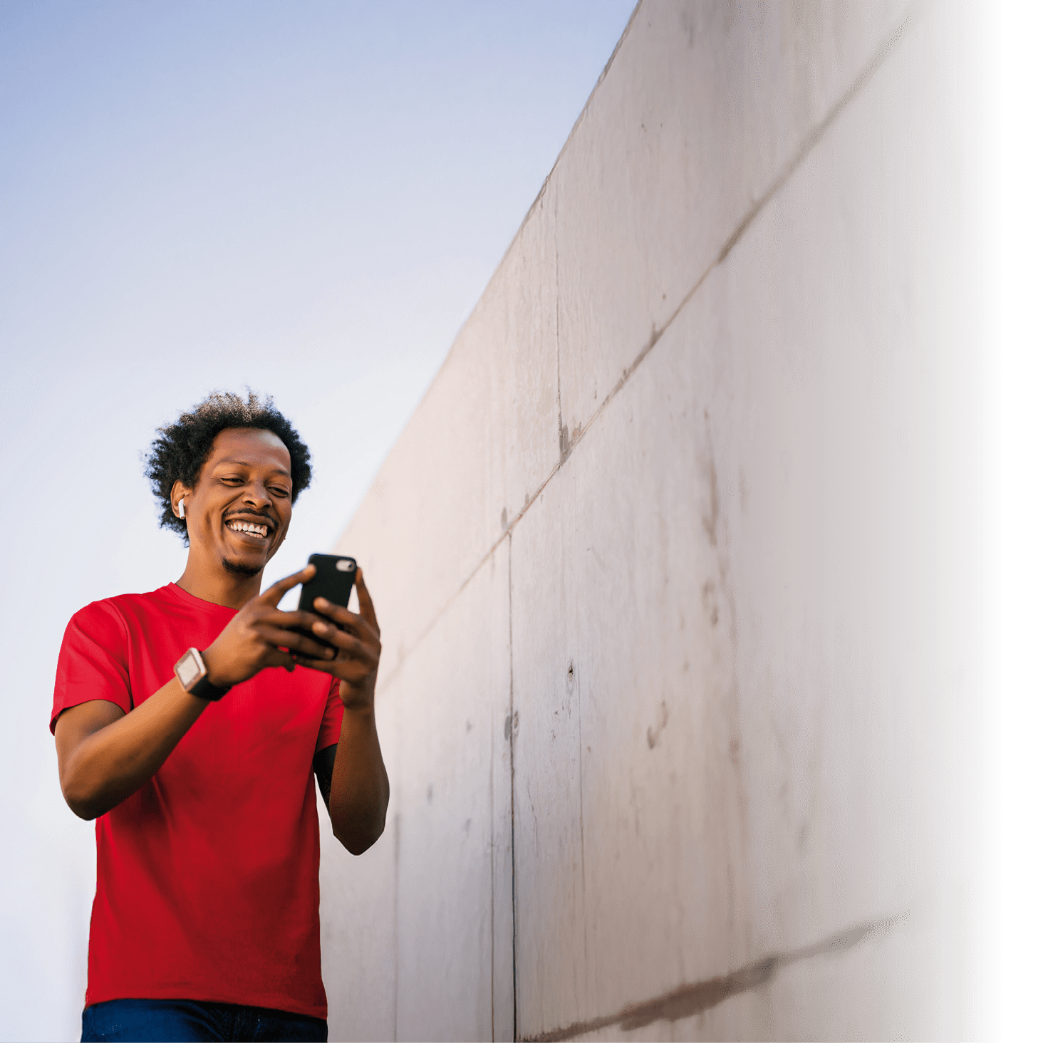 Portrait of afro athlete man using his mobile phone and relaxing after work out outdoors. Sport and healthy lifestyle.