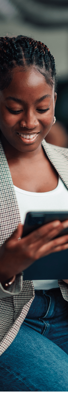 Young black woman smiling and working on a digital tablet, focused and engaged in a modern office environment